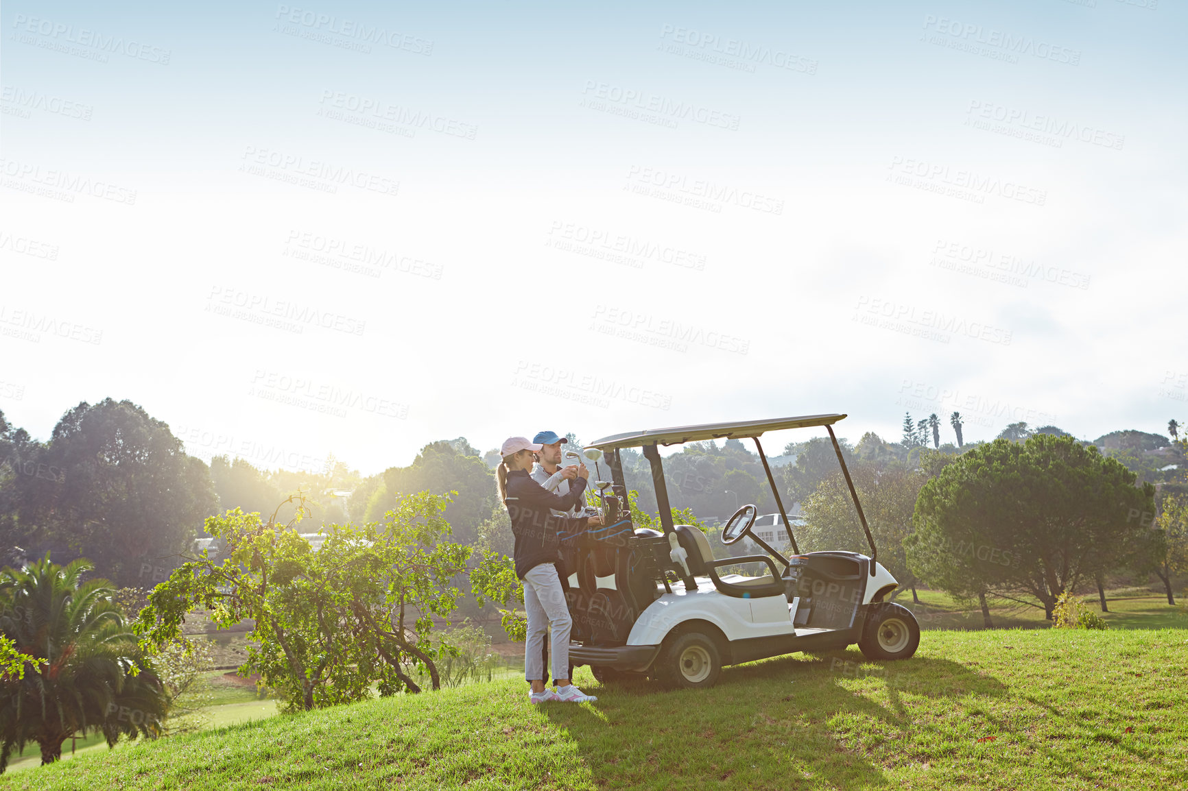 Buy stock photo Shot of a young couple choosing their clubs while enjoying a day on the golf course