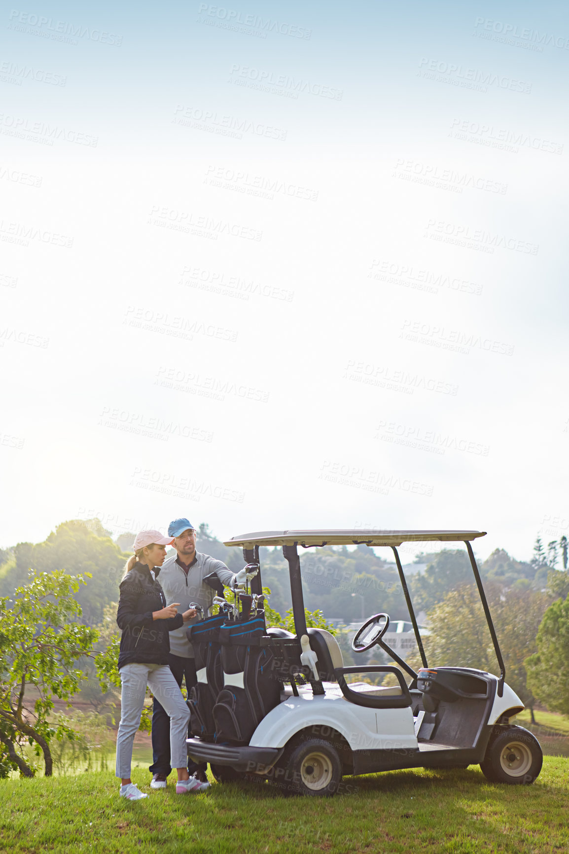 Buy stock photo Shot of a young couple choosing their clubs while enjoying a day on the golf course