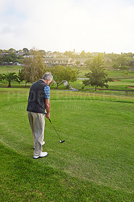 Buy stock photo Full length shot of a senior man lining up a put while enjoying a day playing golf