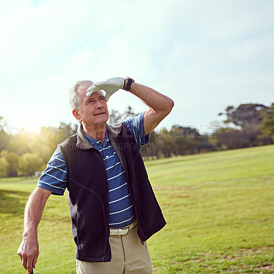 Buy stock photo Shot of a senior man shielding his eyes from the sun while playing golf