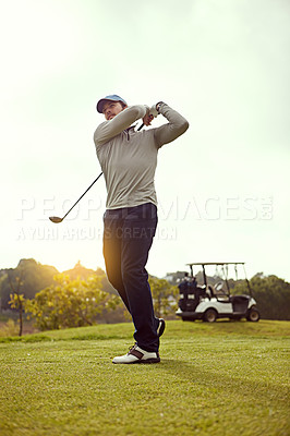 Buy stock photo Full length shot of a young man swining a golf club while enjoying a day on the golf course