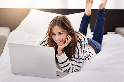 Buy stock photo Shot of a beautiful young woman browsing on a laptop at home