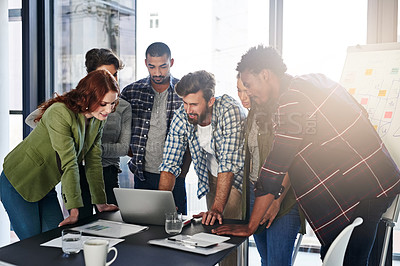 Buy stock photo Shot of a group of colleagues working together on a laptop in an office