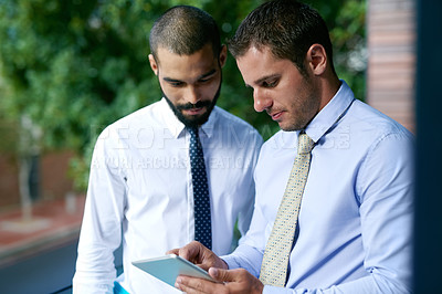 Buy stock photo Cropped shot of two businessmen looking at a tablet in the office