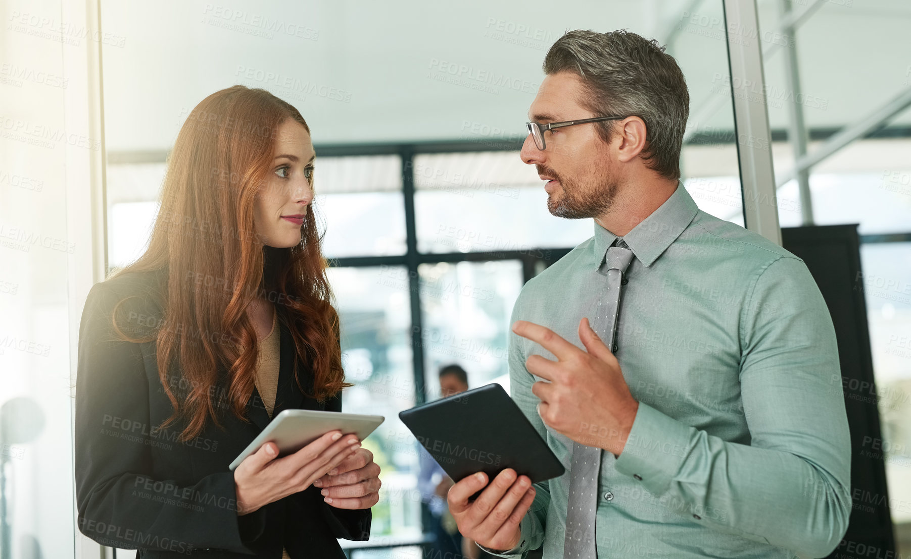 Buy stock photo Cropped shot of two businesspeople using their tablets in the office