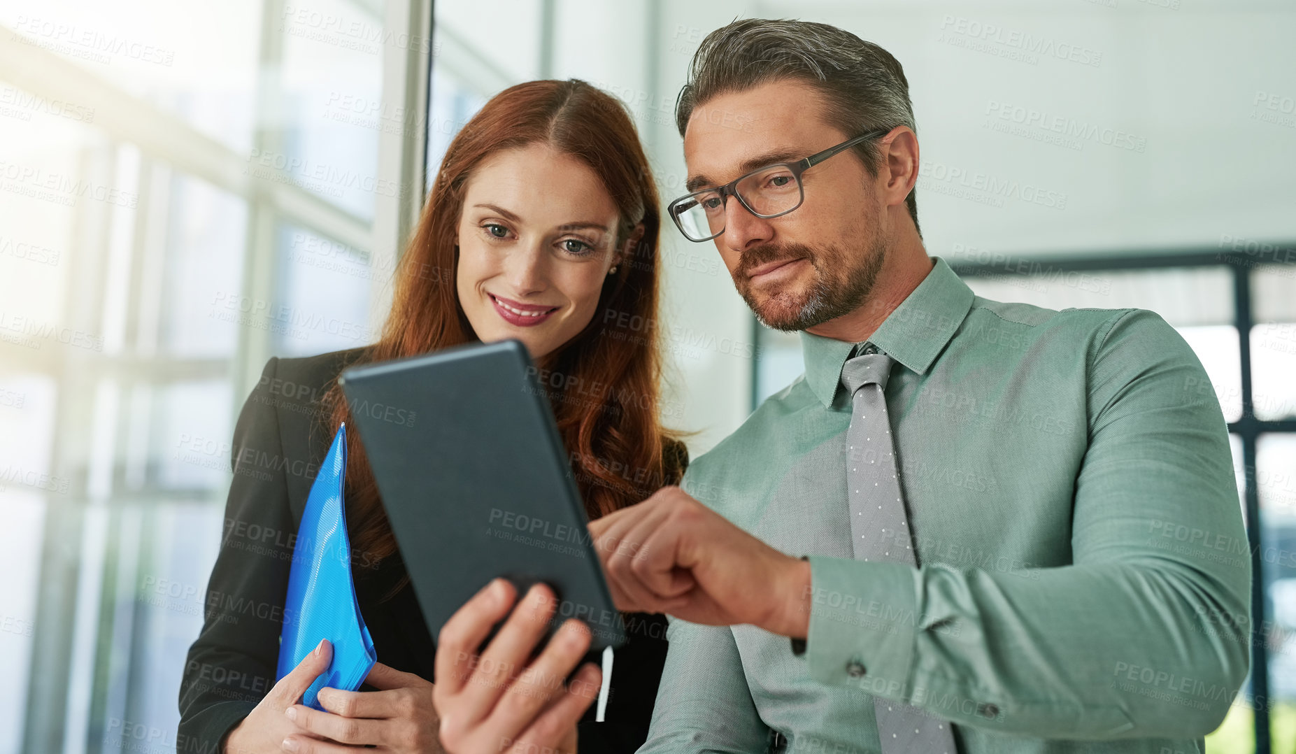 Buy stock photo Cropped shot of two businesspeople looking at a tablet in the office