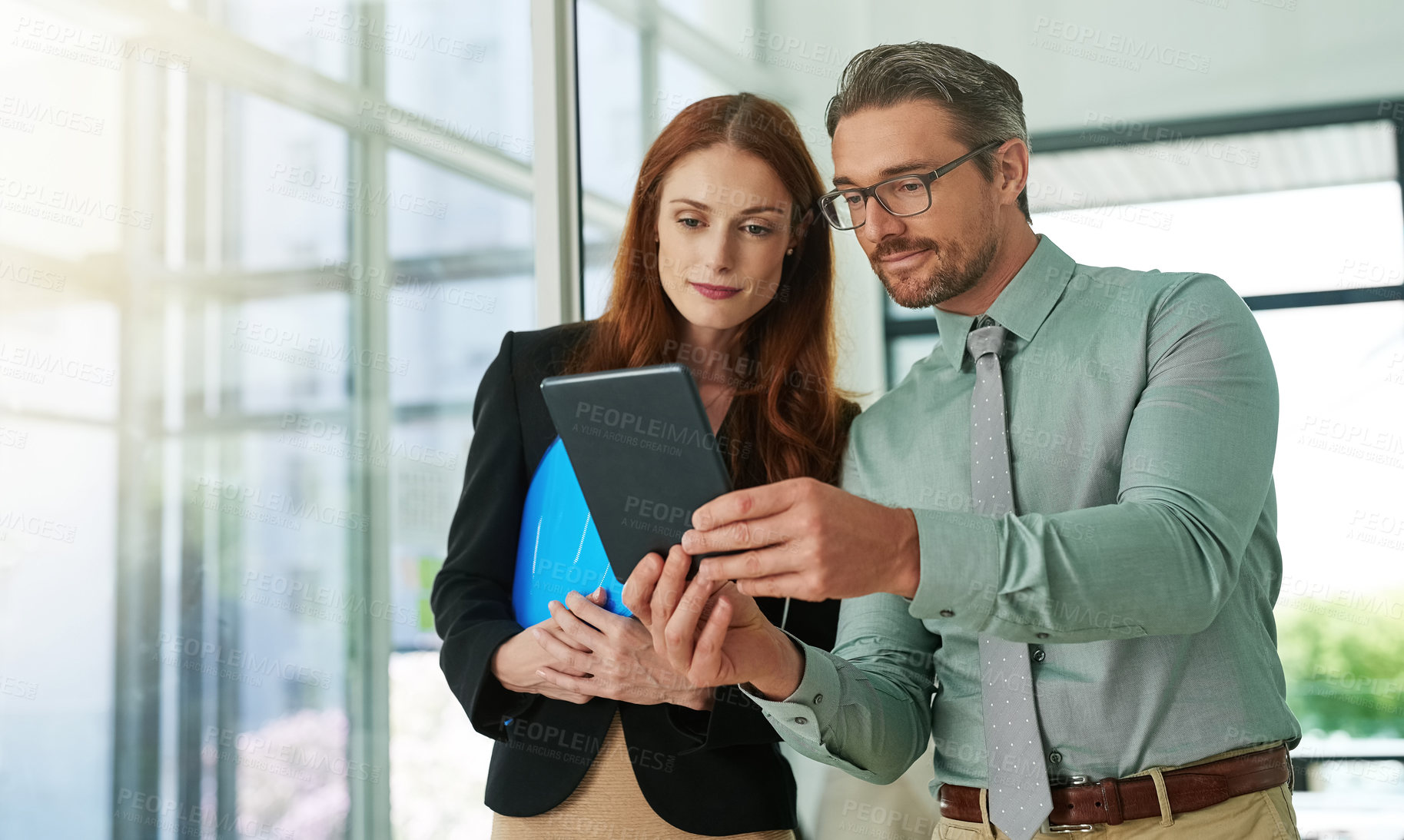 Buy stock photo Cropped shot of two businesspeople looking at a tablet in the office