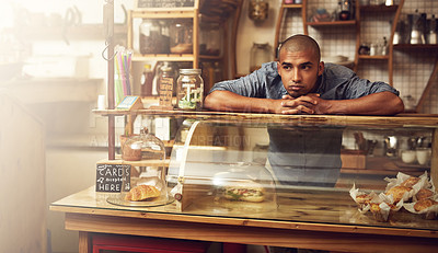 Buy stock photo Shot of a young man standing behind the counter of his store and looking downhearted
