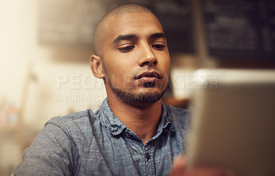 Buy stock photo Shot of a young entrepreneur using a digital tablet in his store