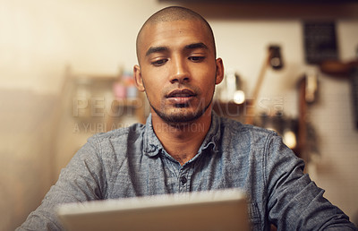 Buy stock photo Shot of a young entrepreneur using a digital tablet in his store