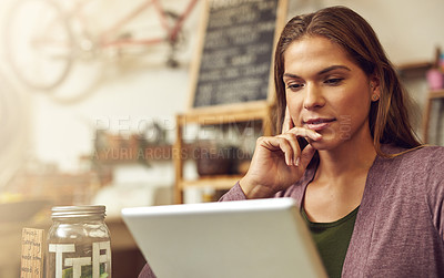 Buy stock photo Shot of a young entrepreneur using a digital tablet in her store