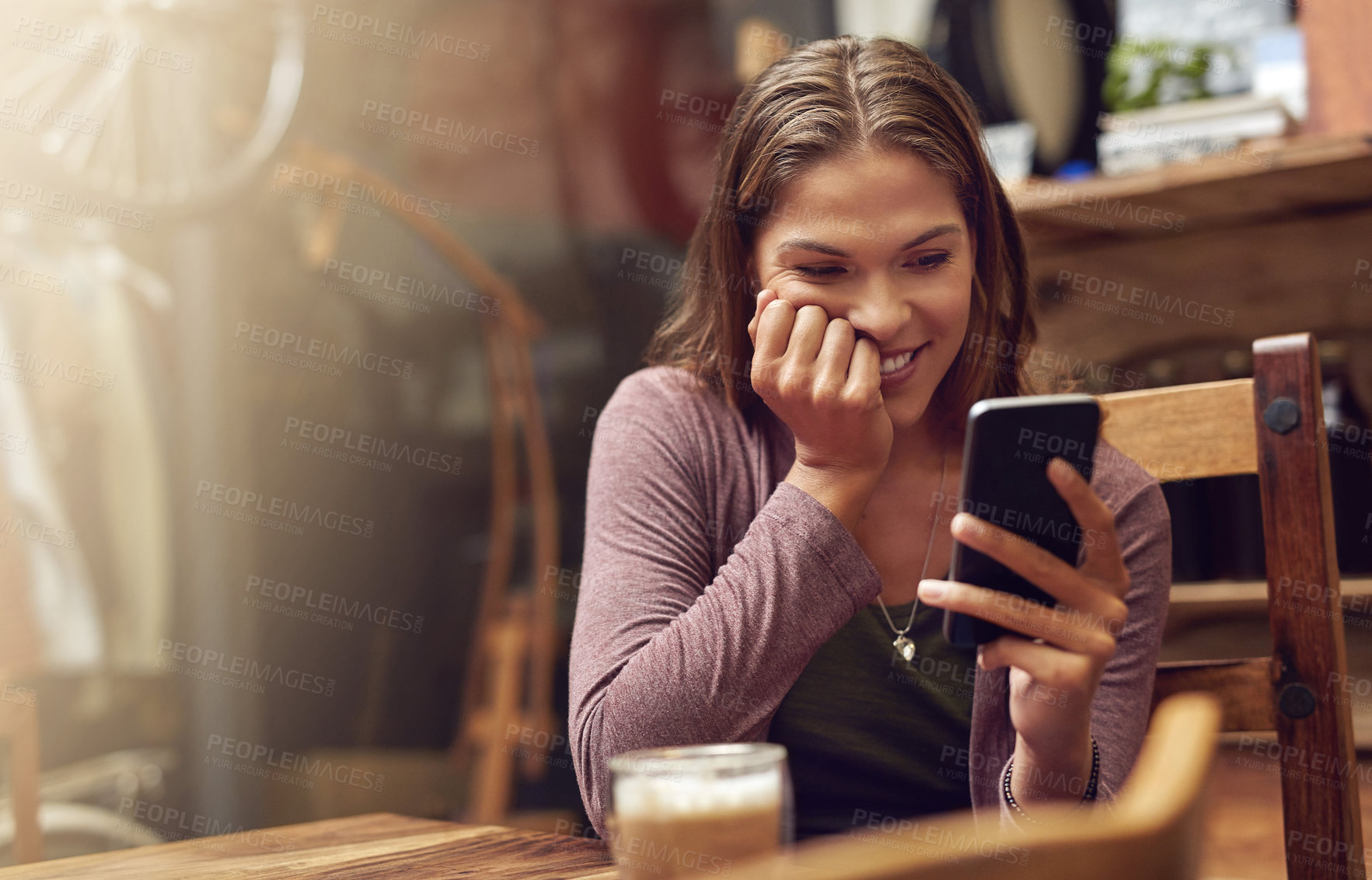 Buy stock photo Shot of a young woman using her phone in a cafe