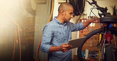 Buy stock photo Shot of a young man using a digital tablet in his bicycle store