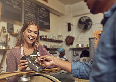 Buy stock photo Shot of a store assistant taking a payment from her customer using his smartphone