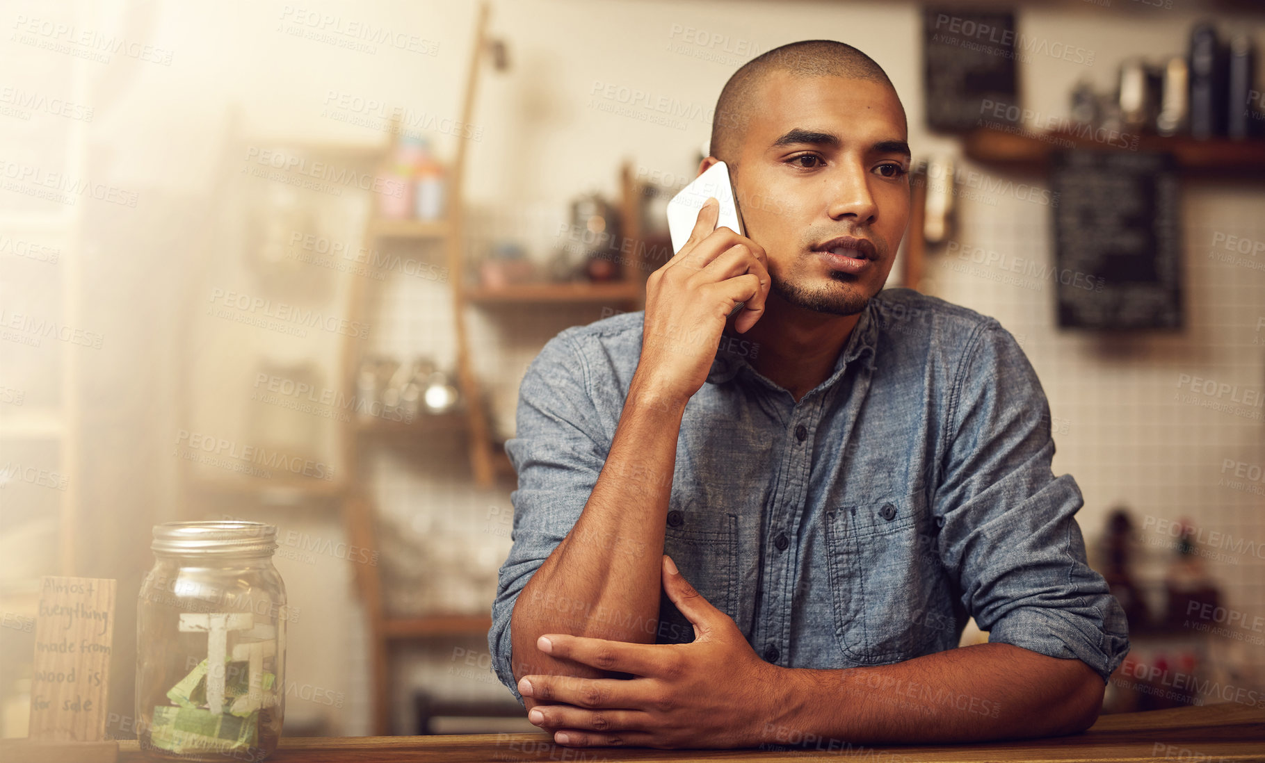 Buy stock photo Shot of a young entrepreneur using a phone in his store