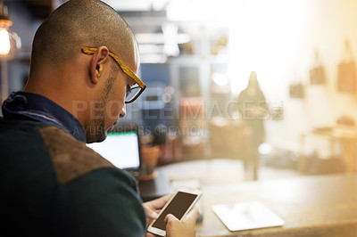 Buy stock photo Cropped shot of a young entrepreneur using a cellphone in his business