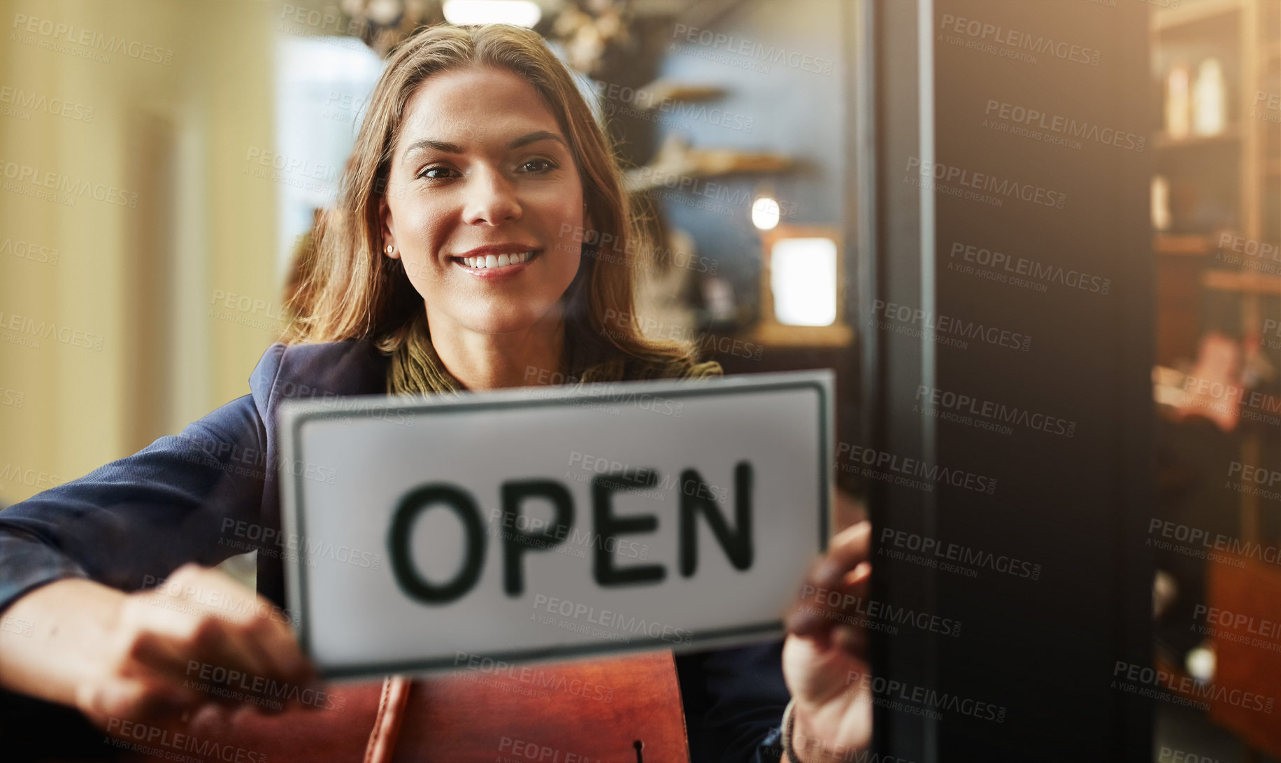 Buy stock photo Portrait of a young business owner hanging up an open sign on the window of her shop
