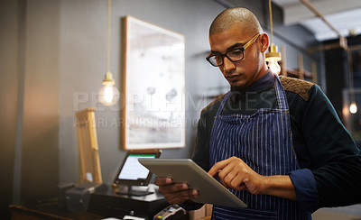 Buy stock photo Cropped shot of a young entrepreneur using a digital tablet in his business