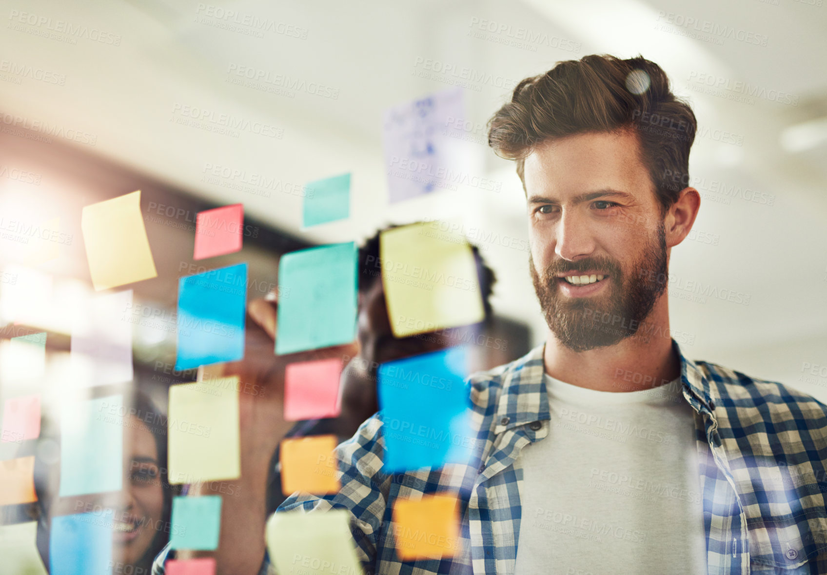 Buy stock photo Cropped shot of coworkers using sticky notes on a glass wall during an office meeting