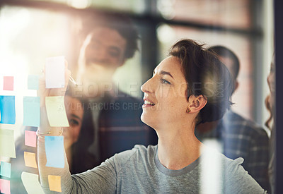 Buy stock photo Cropped shot of coworkers using sticky notes on a glass wall during an office meeting