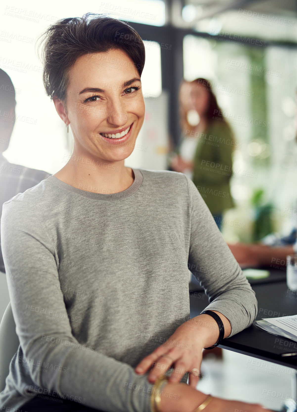 Buy stock photo Portrait of a young businesswoman sitting in a modern office with her colleagues