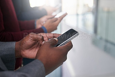 Buy stock photo Shot of a group of colleagues using their cellphones in an office