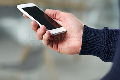 Buy stock photo Cropped shot of a young man holding a cellphone