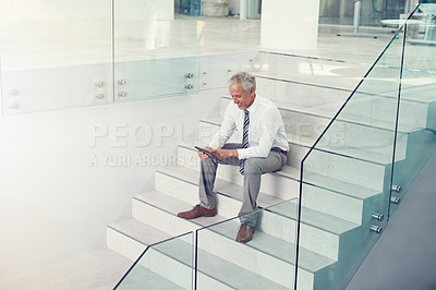 Buy stock photo Full length shot of a businessman using his tablet on the office staircase