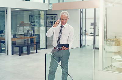 Buy stock photo Cropped shot of a businessman using his tablet while talking on his cellphone