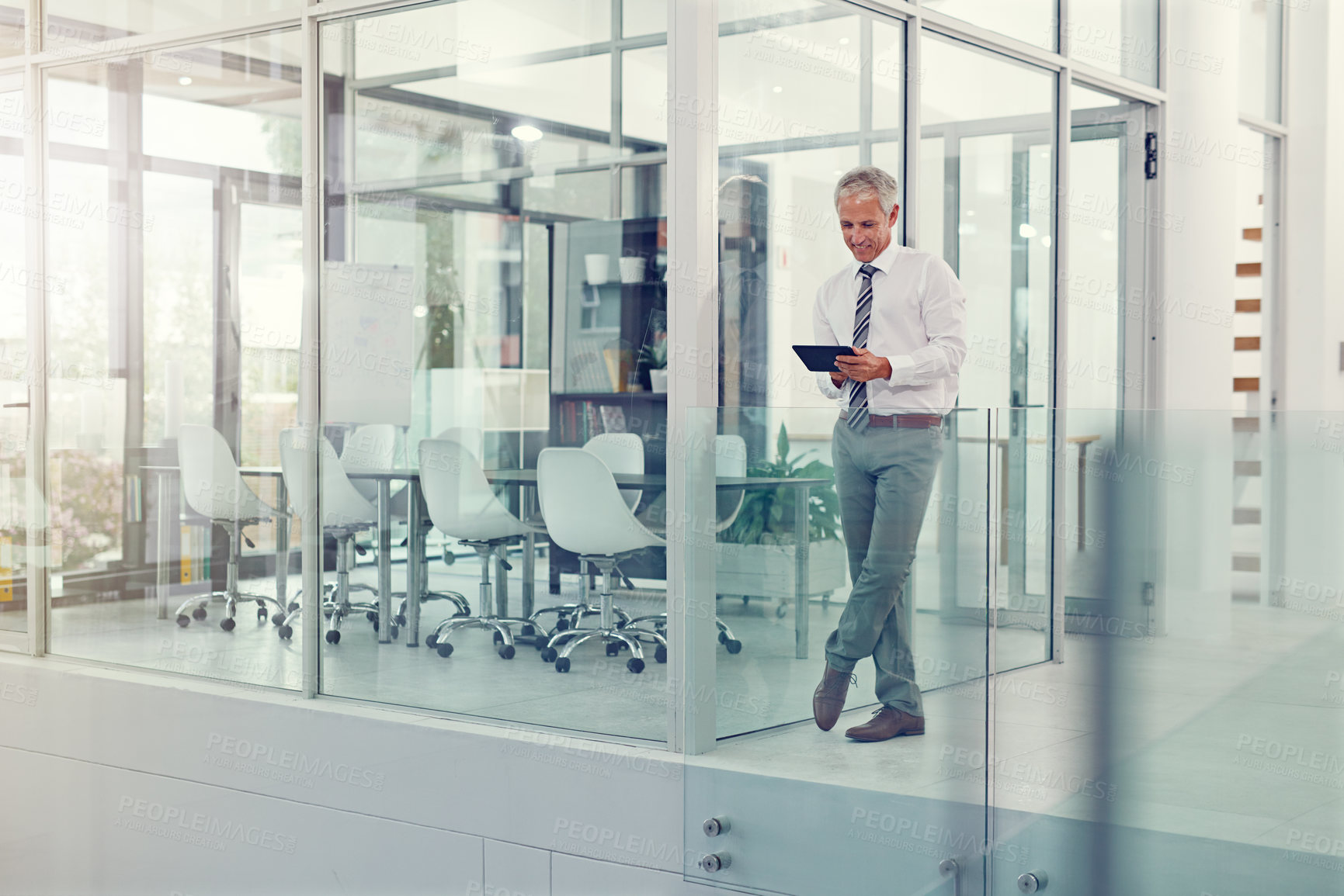 Buy stock photo Full length shot of a businessman using his tablet in the office