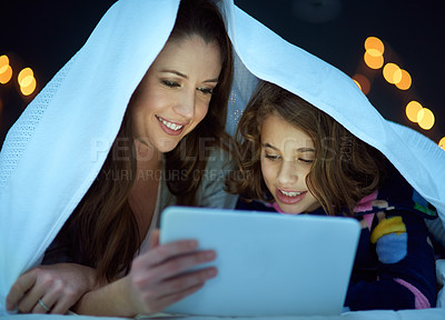 Buy stock photo Mother and daughter lying under a blanket and looking at a tablet