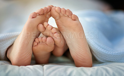 Buy stock photo Cropped shot of a parent and child's feet sticking out under covers