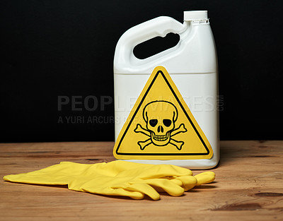 Buy stock photo Shot of a bottle of toxic liquid and a pair of gloves isolated on black