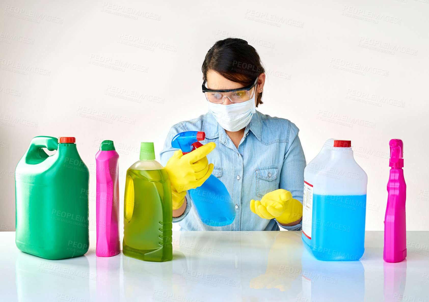 Buy stock photo Cropped shot of a young woman holding various bottles of detergents