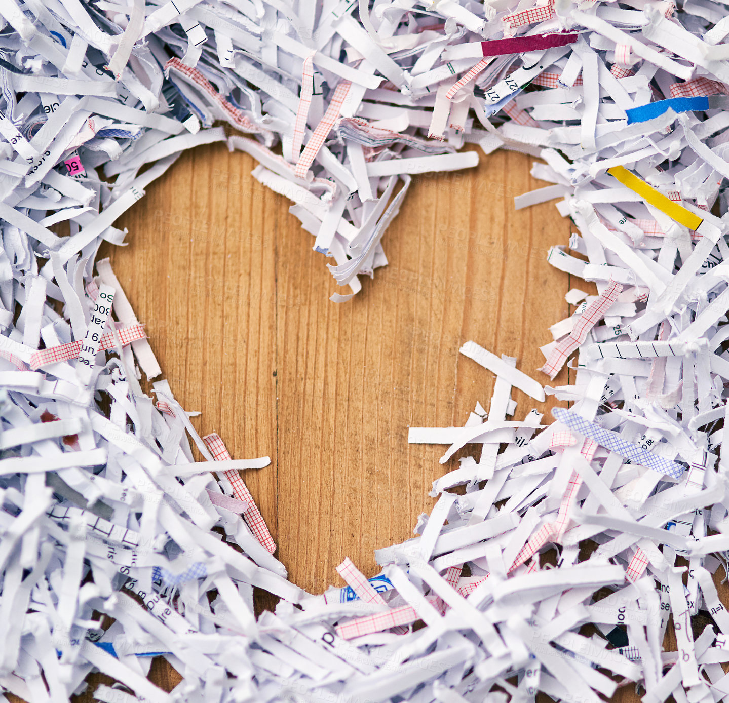 Buy stock photo Studio shot of shredded paper arranged in the shape of a heart on a wooden table