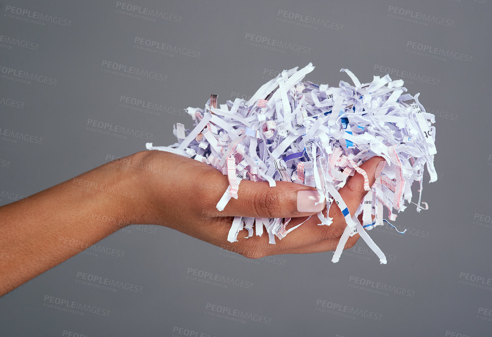 Buy stock photo Studio shot of a woman's hand holding a pile of shredded paper against a grey background