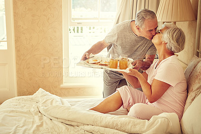 Buy stock photo Shot of a senior man bringing breakfast in bed to his wife