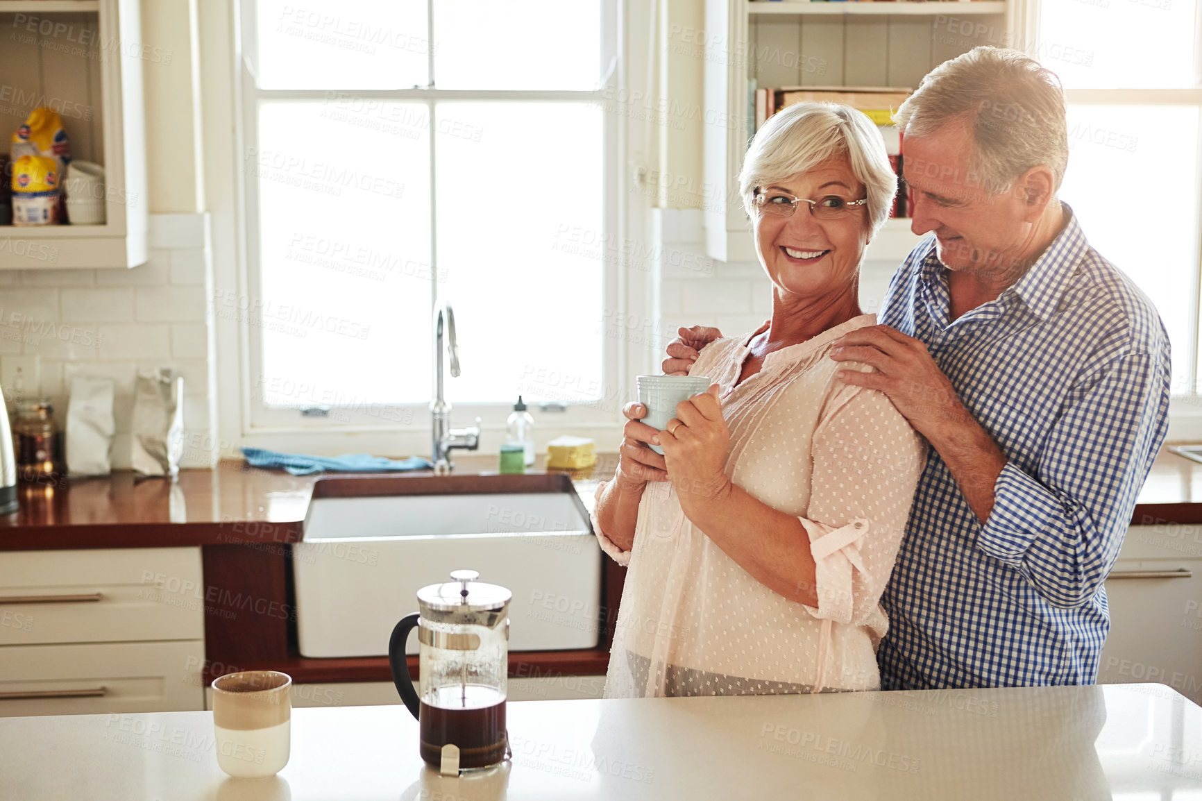Buy stock photo Happy, coffee or old couple hugging in kitchen at home bonding or enjoying quality morning time together. Embrace, retirement or lovely senior man talking, relaxing or drinking tea with mature woman