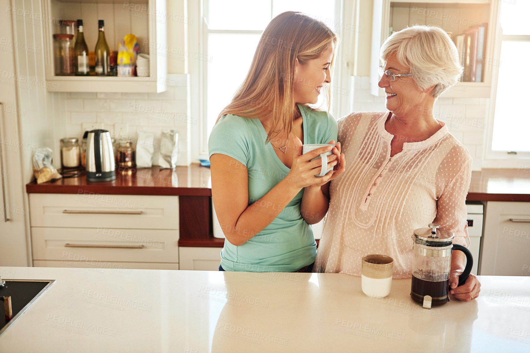 Buy stock photo Mother, coffee or happy woman laughing in kitchen in family home bonding or enjoying quality time together. Embrace, retirement or funny daughter talking, relaxing or drinking tea with senior person 