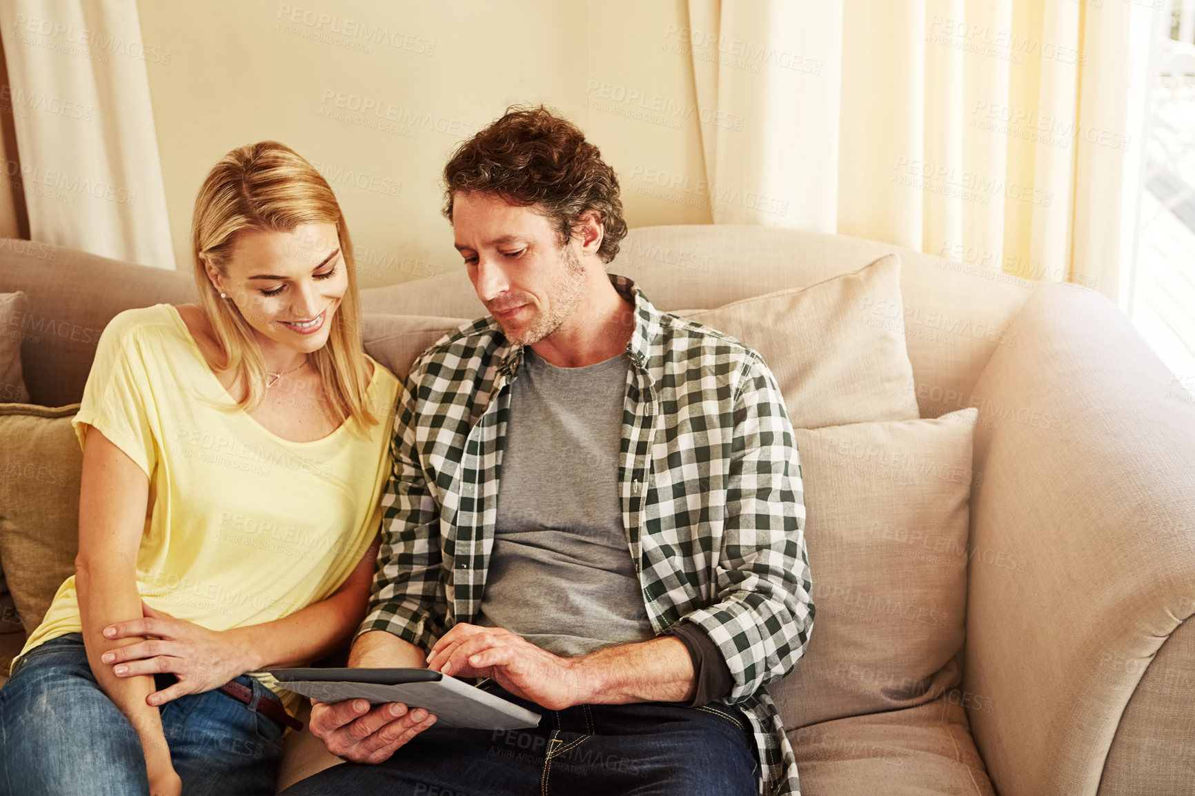 Buy stock photo Cropped shot of a loving couple using their tablet at home