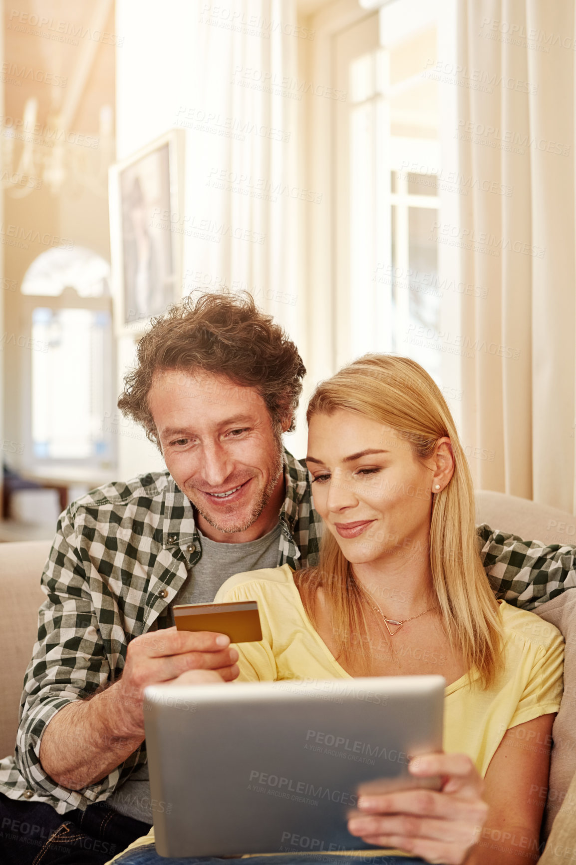 Buy stock photo Cropped shot of a loving couple shopping online on their tablet