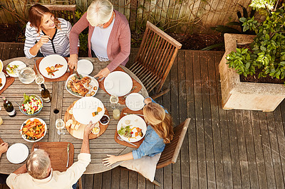 Buy stock photo High angle shot of a family eating lunch outdoors