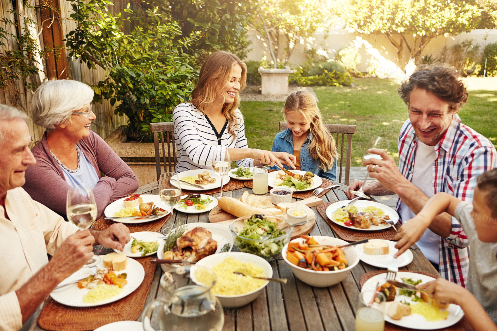 Buy stock photo Helping, love and food with family in nature for thanksgiving event, eating and happiness. Bonding, support and celebration with group of people in garden of home for brunch, wellness and nutrition