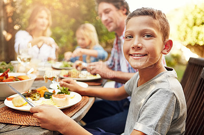 Buy stock photo Portrait of a happy little boy enjoying an outdoor lunch with his family