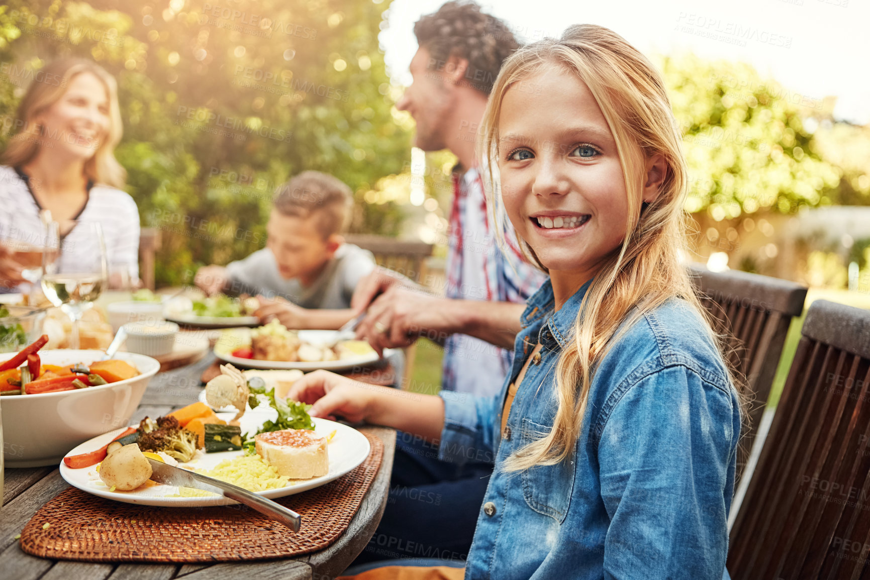 Buy stock photo Portrait of a happy little girl enjoying an outdoor lunch with her family