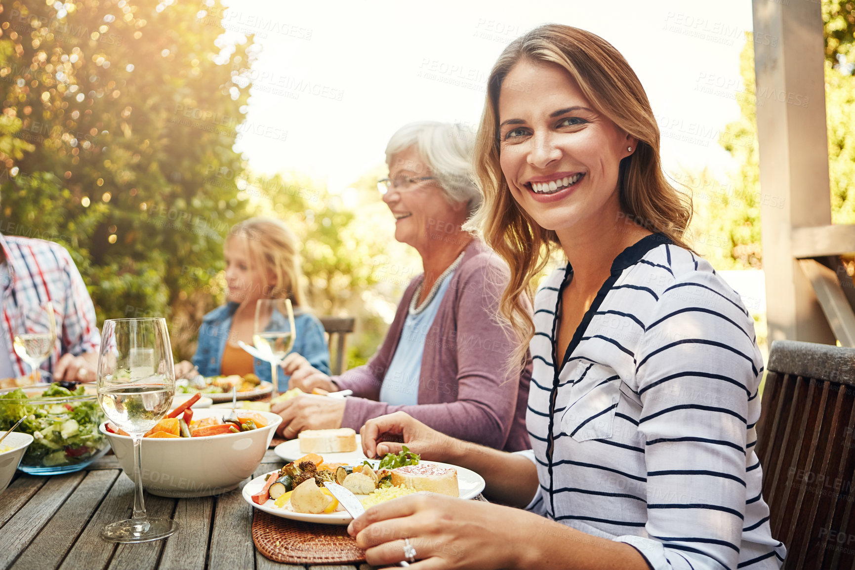Buy stock photo Portrait of a happy woman enjoying an outdoor lunch with her family