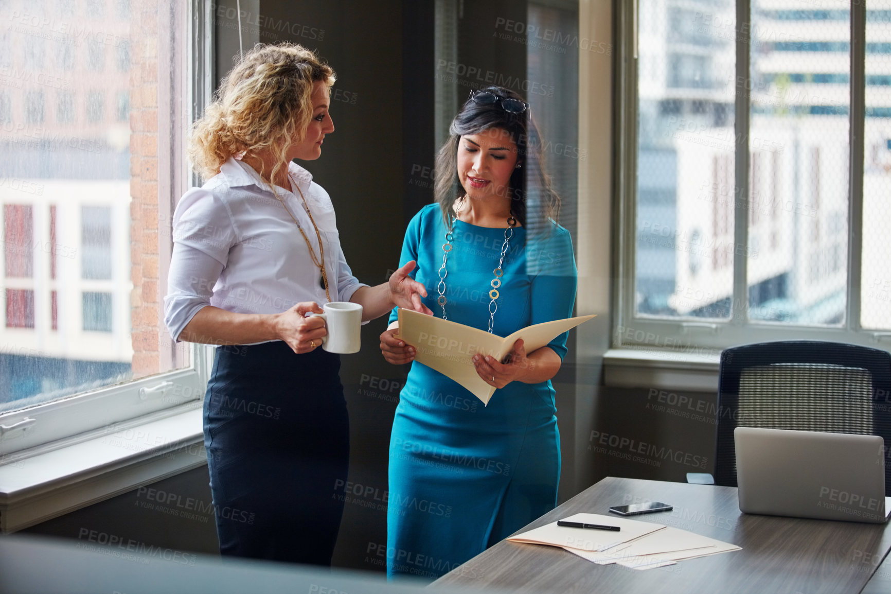 Buy stock photo Shot of two businesswomen going over paperwork together in an office