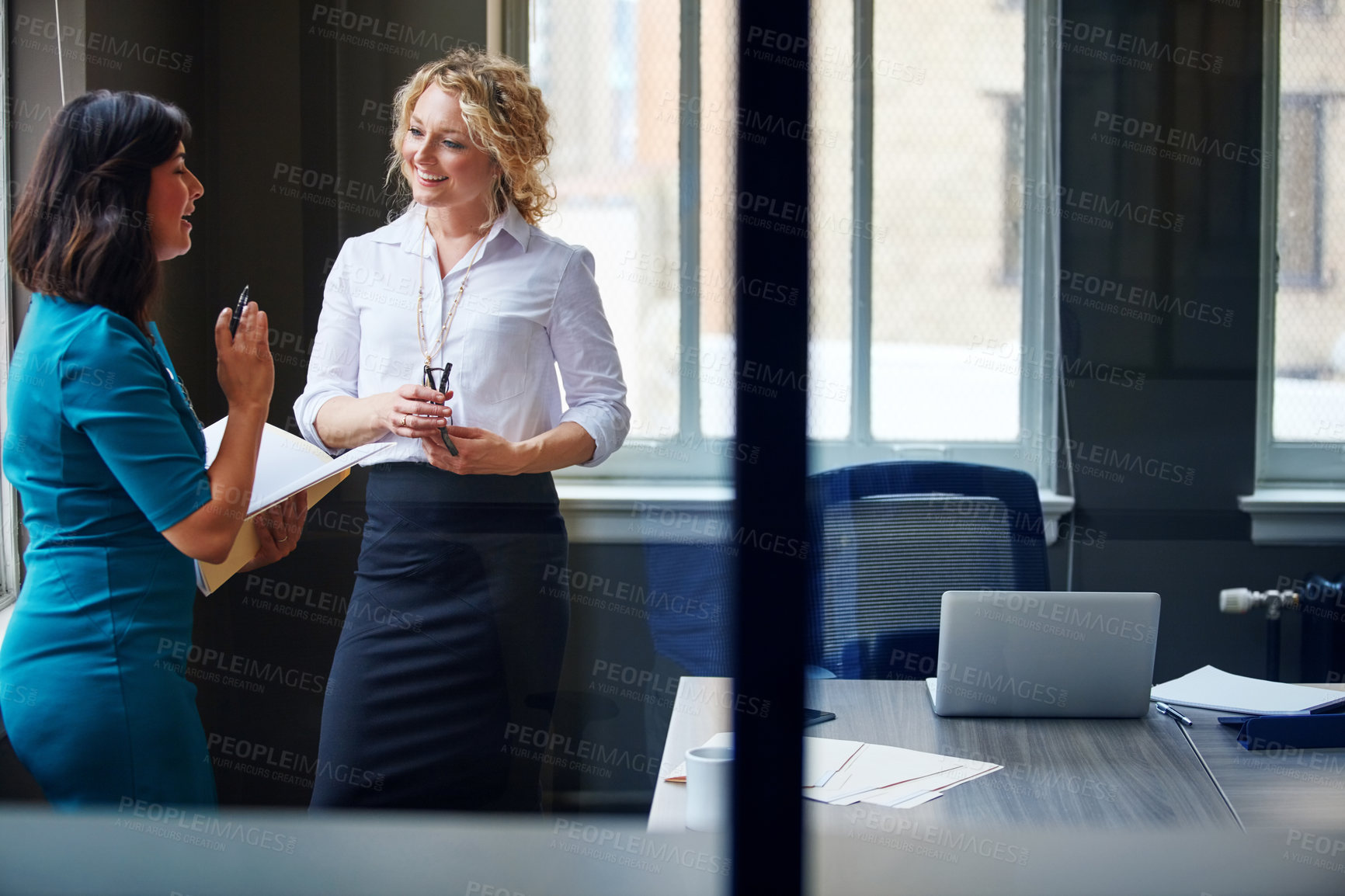 Buy stock photo Shot of two businesswomen having a discussion in an office