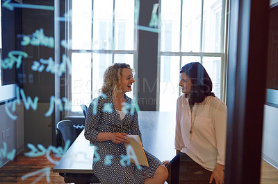 Buy stock photo Shot of two businesswomen talking behind a glass wall with notes writting on it