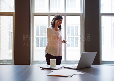 Buy stock photo Shot of a smiling businesswomen talking on a cellphone while standing in an office